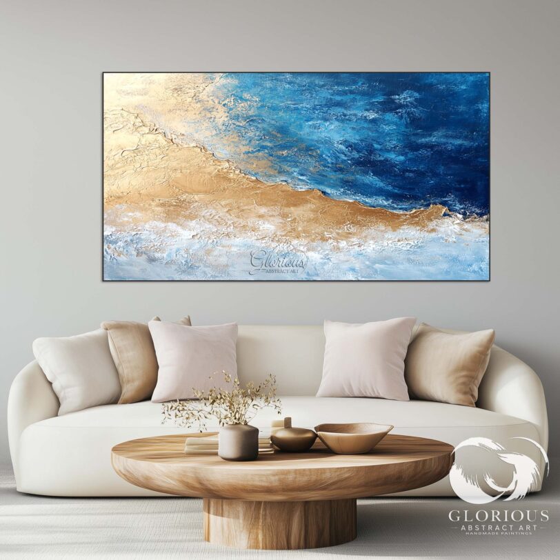 Large coastal abstract painting with blue and gold tones above a beige sofa.